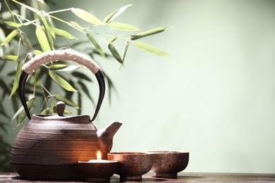 teapot and cups on table with bamboo leaves.