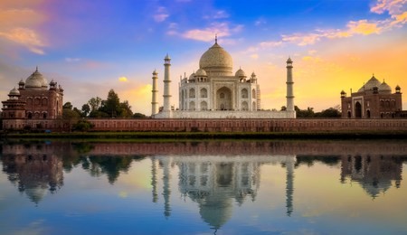 taj mahal agra with mughal architecture gateway at sunset with water reflection.