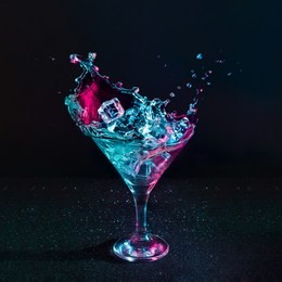 martini cocktail drink splash with ice cubes in neon iridescent pink and blue colors. minimal night party life concept.
