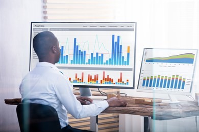 rear view of young businessman looking at graph on the computers in the office