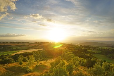 a beautiful sunset, with lens flare, looking towards the royal forest of dean from painswick beacon. this is a very popular viewing point in the cotswolds, gloucestershire, uk