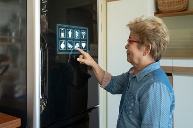 a senior asian woman is touching control panel of display on smart futuristic refrigerator