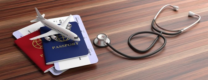 air travelling for health concept. blue and red passports and medical stethoscope isolated on wooden background, banner. 3d illustration