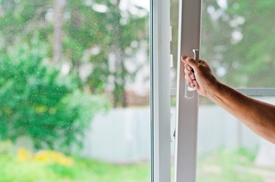 person opens a window with a mosquito net