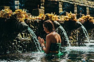 praying in holy spring water of sacred pool at pura tirta empul temple, tampaksiring