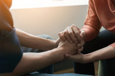 ptsd mental health concept, psychologist sitting and touch hand young depressed asian man for encouragement near window with low light environment.selective focus.