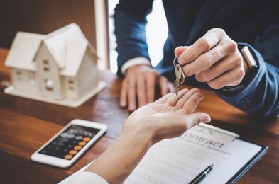 real estate agent sales manager holding filing keys to customer after signing rental lease contract of sale purchase agreement, concerning mortgage loan offer for and house insurance.