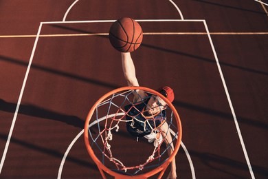 making effort. top view of young man in sports clothing scoring a slam dunk while playing basketball outdoors
