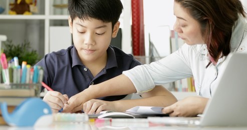 cute asian mother helping your son doing your homework at home with smile face together.