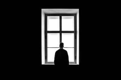 a man's silhouette in front of the window. black and white. concept of loneliness and isolation. 