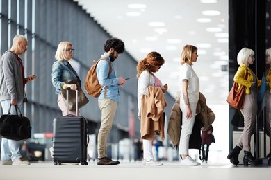 side view of multiracial people standing in queue to check in in airport hall