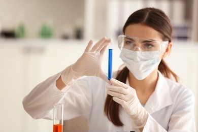 female scientist holding test tube with color sample in laboratory