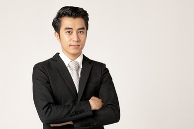 young asian business man in black suit standing cross one's arm on white background. studio close up shot