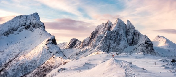panorama of mountaineer standing on top of snowy mountain range at senja, norway