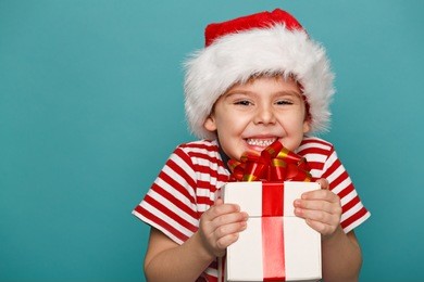 smiling  funny child in santa red hat holding christmas gift in hand. christmas concept.