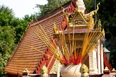 incense sticks burning at a spirit house in front of a pagoda at wat phnom in phnom penh, cambodia.