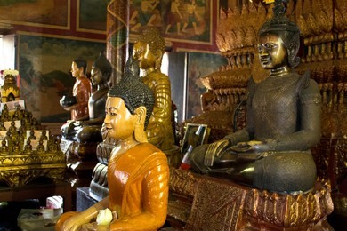some of the many buddhas and the offerings of local people at wat phnom in phnom penh, cambodia.