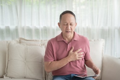 asian old man with chest pain suffering from heart attack in home