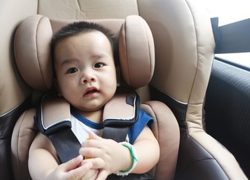 baby in a car seat with a safety belt.