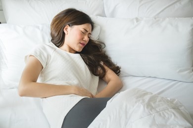 asian woman have menstrual pain in bedroom
