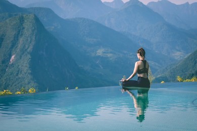 beautiful attractive asian woman practice yoga lotus pose on the pool above the mountain peak in the morning in front of beautiful nature views in sapa vietnam,feel so comfortable and relax in holiday