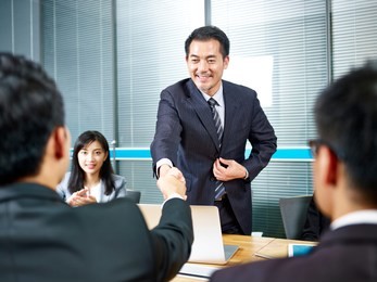 two asian business men shaking hands over meeting table before negotiation.