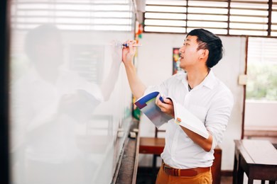 young asian foreign oriental language instructor giving a language lesson in classroom - asian language education concept such as japanese, korean, chinese