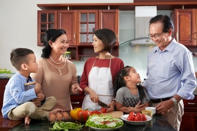 cheerful vietnamese family gathered in kitchen to cook dinner