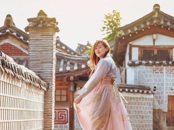 travel and tourist korea concept from beautiful woman in korea traditional cloth (hanbok) relax, take picture in vintage town with rim light and soft focus background