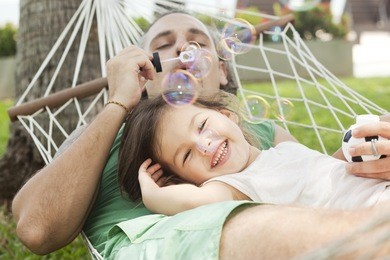 dad and daughter in a hammock blowing bubbles