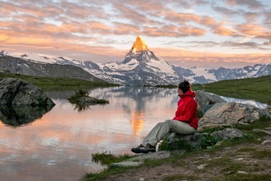 morning shot of the golden matterhorn (monte cervino, mont cervin) pyramid and  blue stellisee lake. female tourist enjoying view of early morning matterhorn mountain is valais alps, switzerland.