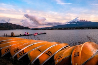 beautiful scenery during sunset of lake kawaguchiko in japan with the rowboat parked on the waterfront and mountain fuji background. travel and attraction concept. kawaguchiko, yamanashi, japan