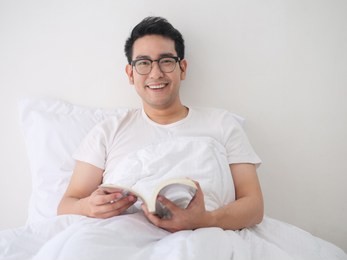 happy asian man reading a book on bed, man lifestyle on weekend concept.