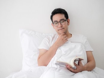happy asian man reading a book on bed, man lifestyle on weekend concept.