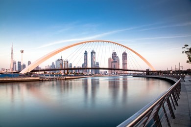 colorful sunset over dubai downtown skyscrapers and the newly built tolerance bridge as viewed from the dubai water canal.