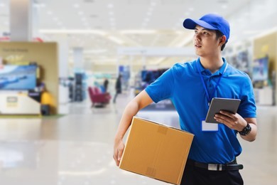 deliveryman holding box and using digital tablet