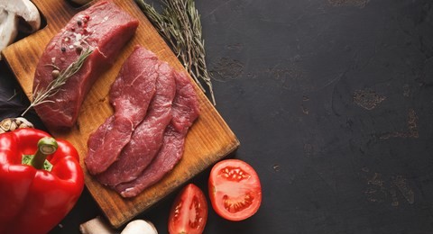 raw filet mignon steaks. fresh beef meat, rosemary on wooden board at black background. organic ingredients for restaurant meals, vegetables, copy space