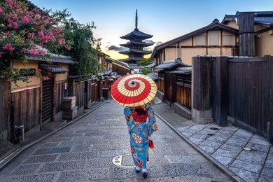 woman wearing japanese traditional kimono with umbrella at yasaka pagoda and sannen zaka street in kyoto, japan.
