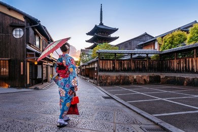 woman wearing japanese traditional kimono with umbrella at yasaka pagoda and sannen zaka street in kyoto, japan.