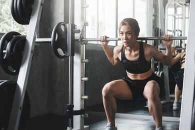 fitness asian woman doing exercise and lifting barbell weights in sport gym, healthy lifestyle concept