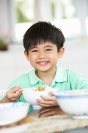 young chinese boy sitting at home eating meal
