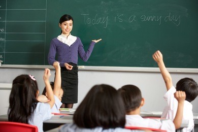 teacher standing by blackboard in chinese school classroom