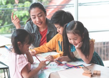 student kids are painting on paper in art group