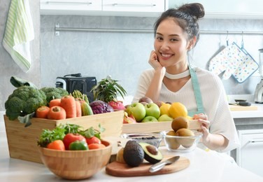 woman in kitchen with various kind of vegetable and fruits that all are good for health and no meat, vegan lifestyle