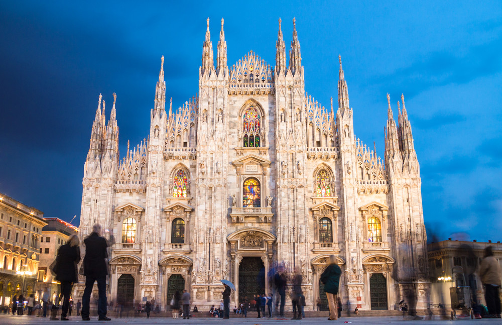 milan cathedral (duomo di milano) is the gothic cathedral church of milan, italy. shot in the dusk from the square ful of people.