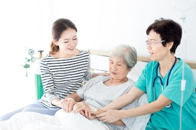doctor and asian female talk with old asian patient about disease symptom , elderly health care , palliative care, they  holding hand of patient, mother day