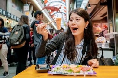 pretty girl picking up sashimi on the table. a traditional market in japan full with food and crowd.