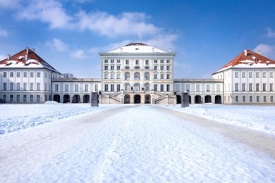 germany, bavaria, munich, nymphenburg palace: panorama view of winter scene with main building entrance of the famous castle, white icy snow, blue sky in the bavarian capital.
