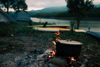 camp and cooking in field conditions, boiling pot at the campfire on picnic in morning.  cooking dinner on firewood stove using firewood when going to the wilderness or outdoor activity, camping tent