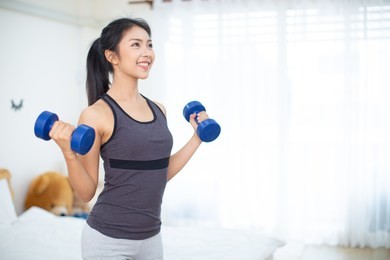 sporty beautiful woman exercising with dumbbell at home to stay fit